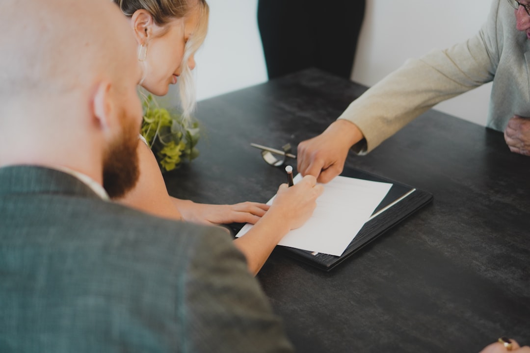 G1 Gestoría Advisor explaining a family protocol to a couple signing documents at a dark table